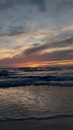 the sun is setting over the ocean with waves