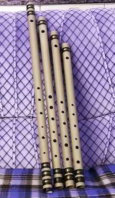 three flutes sitting next to each other on top of a purple cloth covered bench with black polka dots