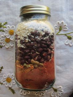 a jar filled with lots of different types of food on top of a white table cloth