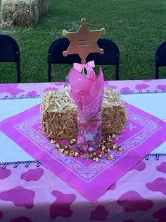 a pink table cloth with a star on top and some hay in the middle is set up as a centerpiece