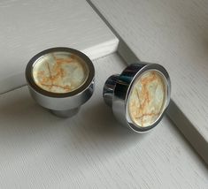 two metal knobs sitting on top of a white counter next to a window sill