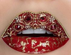 a woman's mouth with red and gold decorations on it, as if she is wearing