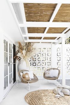 two wicker chairs sitting on top of a white floor under a pergolated roof