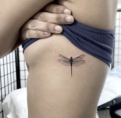 a woman's thigh with a small dragonfly tattoo on her left side ribcage