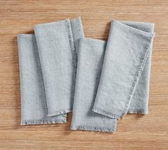 three folded linen napkins on a wooden surface