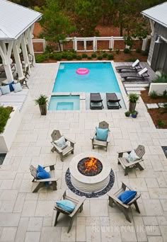 an aerial view of a fire pit surrounded by lawn chairs and loungers with a pool in the background