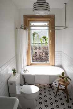 a bathroom with black and white tile flooring and a bathtub next to a window