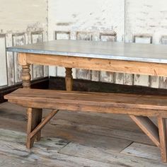 an old wooden bench sitting in front of a white brick wall