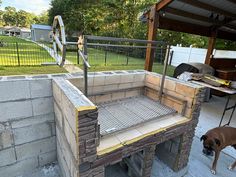 a dog standing in front of a brick oven on top of a cement block wall