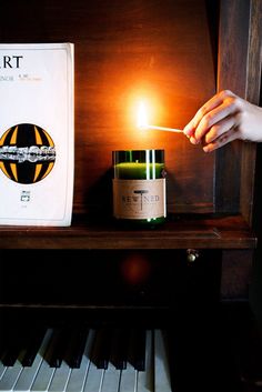 a person lighting a candle on top of a piano