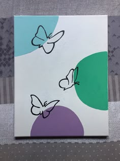 a painting with butterflies painted on it sitting next to a gray and white striped wall