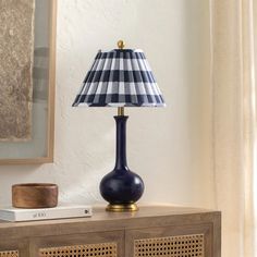 a blue lamp sitting on top of a wooden table next to a book and vase