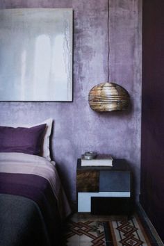 a bedroom with purple walls and a large painting on the wall next to a bed