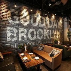 a brick wall in a restaurant with tables and couches around it, surrounded by lights