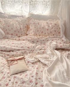 an unmade bed with white sheets and pink flowers