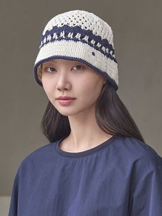 a woman wearing a knitted hat while standing in front of a wall