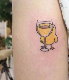 a small yellow bird with a wine glass tattoo on the arm