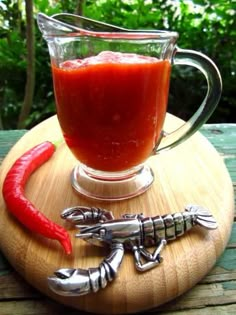 a glass cup filled with liquid next to a red chili pepper on a wooden table