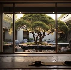 a bonsai tree is seen through an open window in a japanese style room with two tea cups on the table