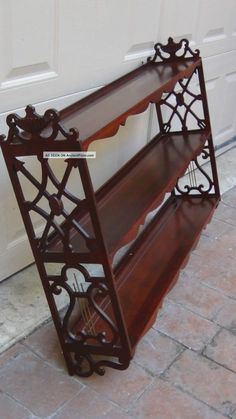 a wooden shelf sitting on the side of a door next to a brick floor and white garage door