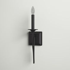 a black wall light with a single candle on it's side and a white background