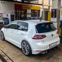 a white car parked in front of a gas station