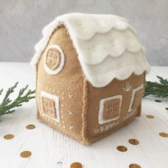 a gingerbread house with white roof and snow on the top, surrounded by gold coins