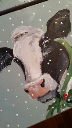 a painting of a black and white cow with holly on it's head is shown