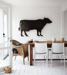 a dining room table with chairs and a cow on the wall