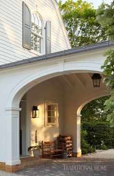 the front entrance to a house with an arched doorway and white siding on it's side