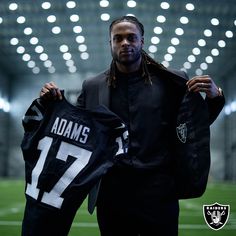 a man holding up a jersey with the number 17 on it in front of an empty stadium