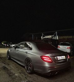 a car parked in a parking lot at night with its lights on and it's rear end showing