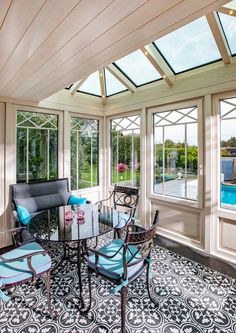 a sun room with glass walls and lots of windows on the ceiling is filled with furniture