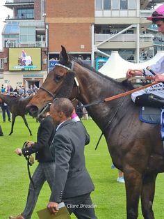 a man in a suit riding on the back of a horse next to another man