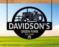 the logo for davidson's green farm is hanging from a chain in front of a field