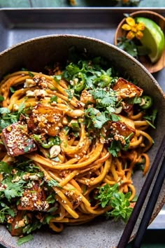 a bowl filled with noodles and vegetables next to chopsticks