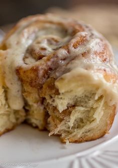 a cinnamon roll on a white plate with a bite taken out of the top one