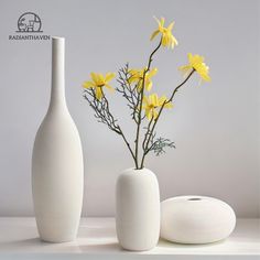 two white vases with yellow flowers in them