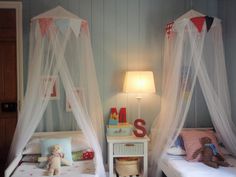 two beds with mosquito netting on them in a child's playroom or bedroom