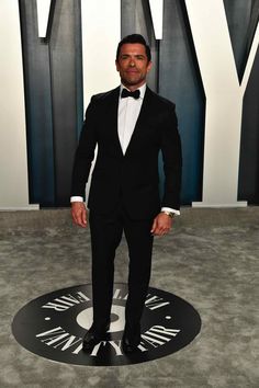 a man in a tuxedo and bow tie posing for the camera at an event