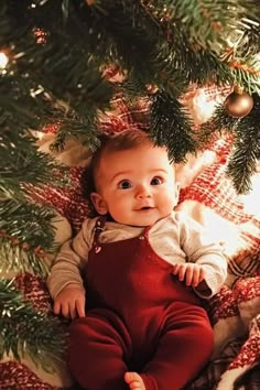 a baby sitting in front of a christmas tree