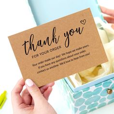 a person holding up a thank you card in a box with some writing on it