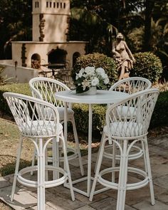 three white wicker bar stools around a table