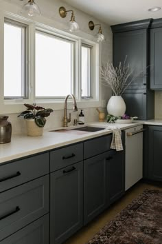 a kitchen with gray cabinets and white counter tops, along with a rug on the floor