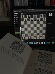 an open book sitting on top of a laptop computer next to a chess game set