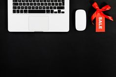 a white laptop computer sitting on top of a desk next to a mouse and red ribbon