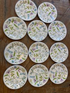 six plates with floral designs on them sitting on a wooden table