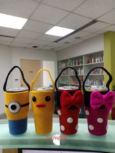 three crocheted bags with faces and bows on them sitting on a counter in an office