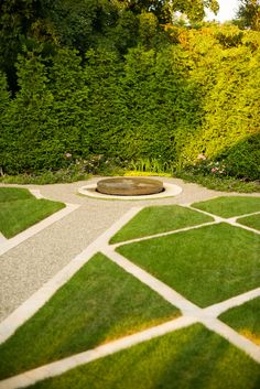 a garden with grass and stepping stones in the center, surrounded by shrubbery on either side