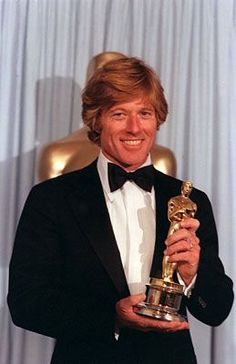 a man in a tuxedo holding an oscar award for best performance by an actor